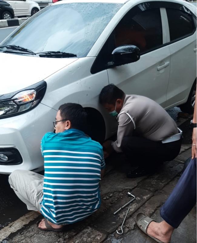 Kanitlantas Bekasi Timur, Iptu M Sahari memberikan pertolongan ke pengendara mobil yang mengalami ban bocor di depan Pos Polisi Bekasi Timur, Sabtu (20/11/2021). Foto: ist.