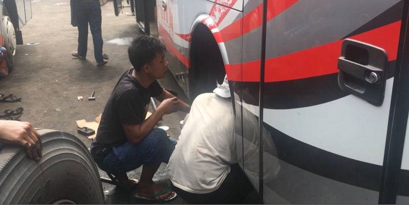 Ellan (kaos hitam) kru bus Ranau Indah saat perbaiki bus. Foto: BeritaTrans.com.