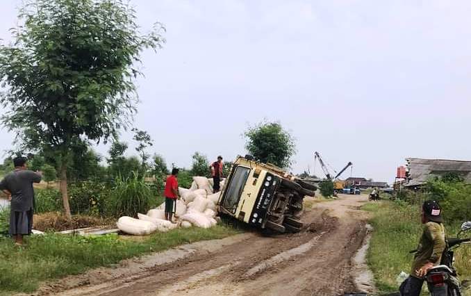 Truk colt diesel muatan puluhan karung dedak kasar terguling di jalan rusak di wilayah Desa Karanganyar, Kecamatan kandanghaur, Indramayu, Jawa Barat. (Taryani)