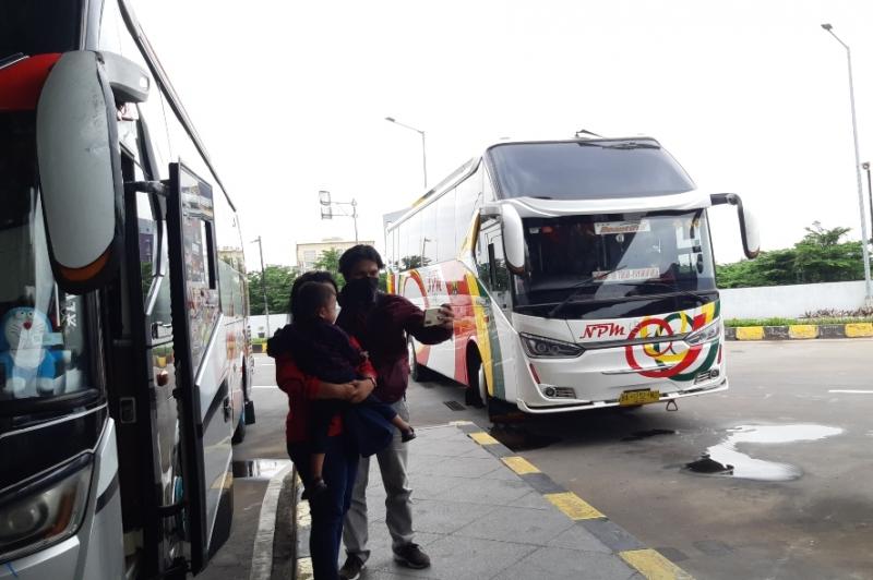 Penumpang bus berswafoto leluarga dengan latar belakang bus yang akan dinaikinya dari Terminal Pulo Gebang, Jakarta Timur, Rabu (1/12/2021).