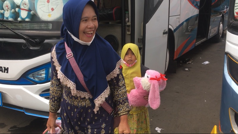 Seorang bocah dengan menggendong bonek miliknya ditemani seorang ibu, semangat berjalan menuju bus Ranau Indah di Terminal Bekasi, Rabu (15/12/2021). Foto: BeritaTrans.com.