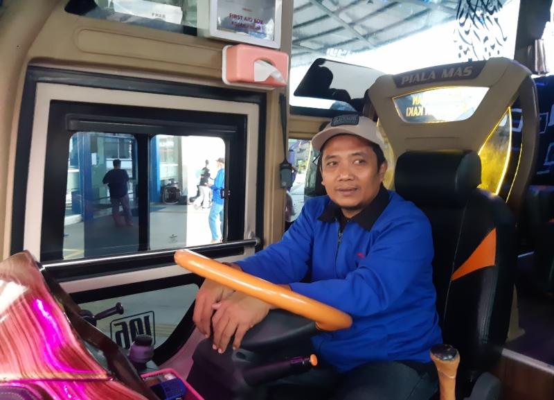 Edi pengemudi bus Haryanto saat menaikkan penumpangnya di Terminal Pulo Gebang, Jakarta, Jumat (24/12/2021). 