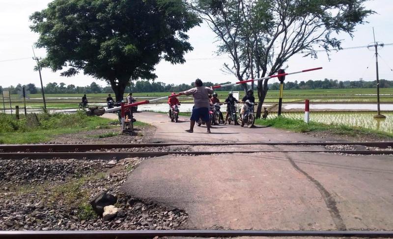 Kang Gendut membuka  pintu perlintasan KA di Blok Nomik, Desa Kedokan Gabus, Kecamatan Gabuswetan, Indramayu, Jawa Barat. (Taryani)