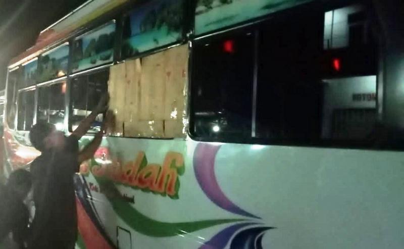 Awak bus Paris Indah menutup kaca samping yang pecah dengan lakban setelah  dilepar pemuda mabuk. (Foto:Media Kupang)