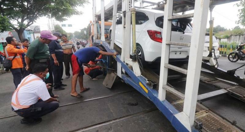 Petugas mengevakuasi truk pengangkut mobil profit yang tersangkut di perlintasan KA Kota Kediri. (Foto:Antara) 