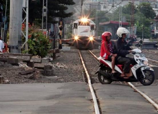 Ilustrasi seorang pengendara membonceng wanita nekad menyeberangi rel saat kereta api akan melintas sehingga membahayakan keselamatan pengendara. (Ist.)