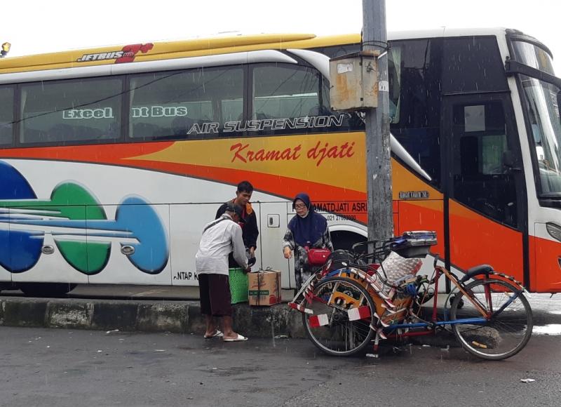 Di tengah guyuran hujan penumpang bus mengakhiri perjalanan di terminal Bekasi dengan bus dan akan melanjutkan lagi menggunakan becak, Rabu (26/1/2022).