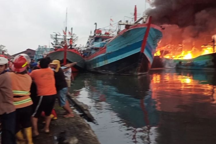 Petugas damkar bersama nelayan berusaha memadamkan kobakaran api yang membakar kapal di Pelabuhan Tegal, Jawa Tengah, Sabtu (29/1/2022). Foto: kompas.com.