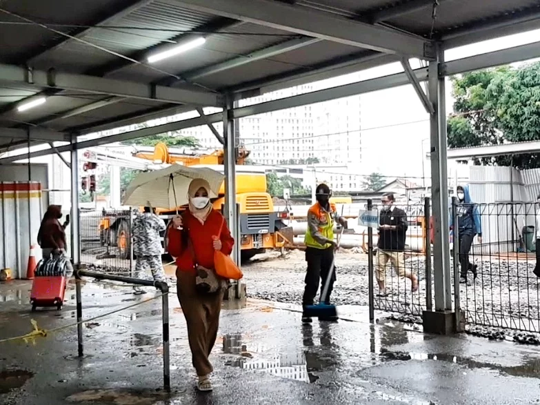 Petugas membersihkan genangan di jalur masuk di penyeberangan peron Stasiun Bekasi, Senin (7/2/2022).