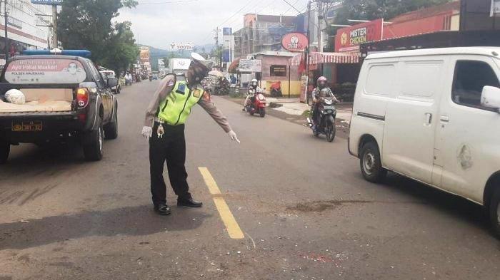 Petugas kepolisian menunjukkan jalan rusak atau berlubang. (Foto:TribunManado)