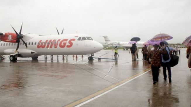 Ilustrasi - Sejumlah penumpang pesawat menggunakan payung berjalan menuju pesawat di Bandara El Tari Kupang, NTT. Antara/Kornelis Kaha