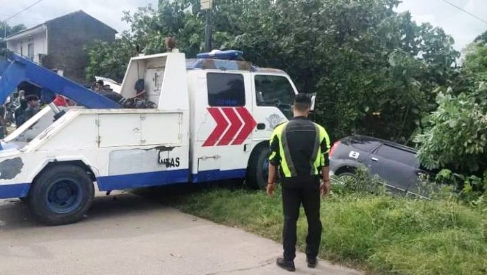 Petugas menderek Toyota Avanza yang nyungsep ke tepi sawah di jalan lingkar selatan (JLS)  Cilegon, Provinsi Banten.  (Foto:detik.com)