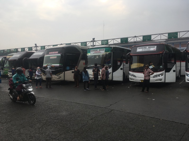 Bus anatarkota di area keberangkatan Terminal Bekasi di tengah guyuran hujan, Jumat (1/4/2022) sore. Foto: BeritaTrans.com.