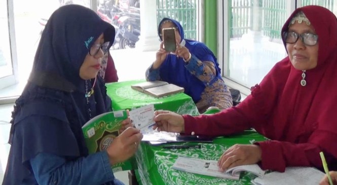 Seorang ibu sesudah mengaji 1 juz memperoleh i kupon yang bsia ditukar 1 liter Pertamak di SPBU milik Bupati Ngawi. (Foto.Dok.tvonenews.com)