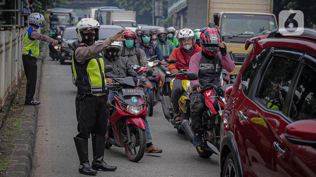 Anggota polisi mengatur lalu lintas saat ganjil genap di kawasan Jalan D.I Panjaitan, Jakarta.