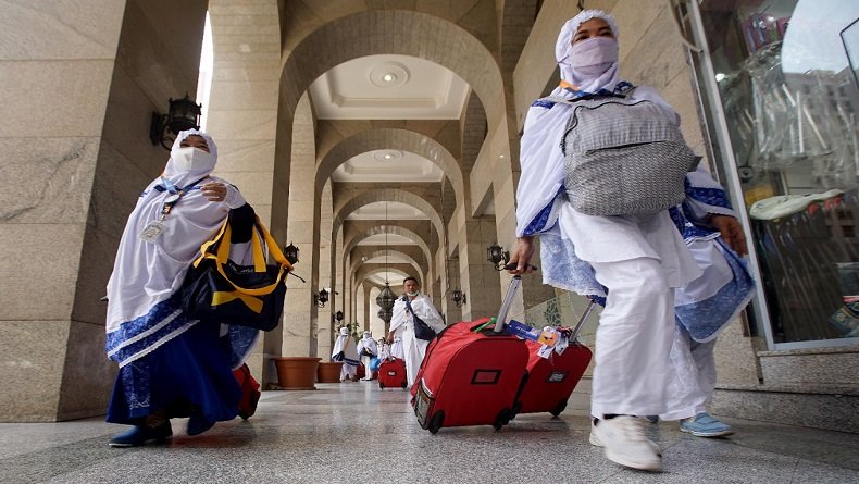 Jemaah haji perempuan Indonesia mengenakan masker saat meninggalkan hotel di Madinah menuju ke Mekah.