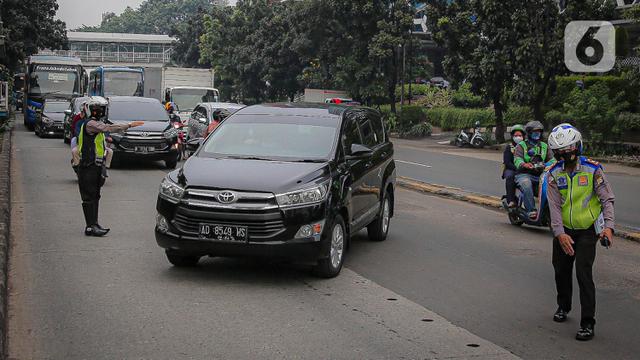 Anggota polisi melakukan penindakan kepada sebuah kendaraan saat ganjil genap di kawasan Jalan D.I Panjaitan, Jakarta.