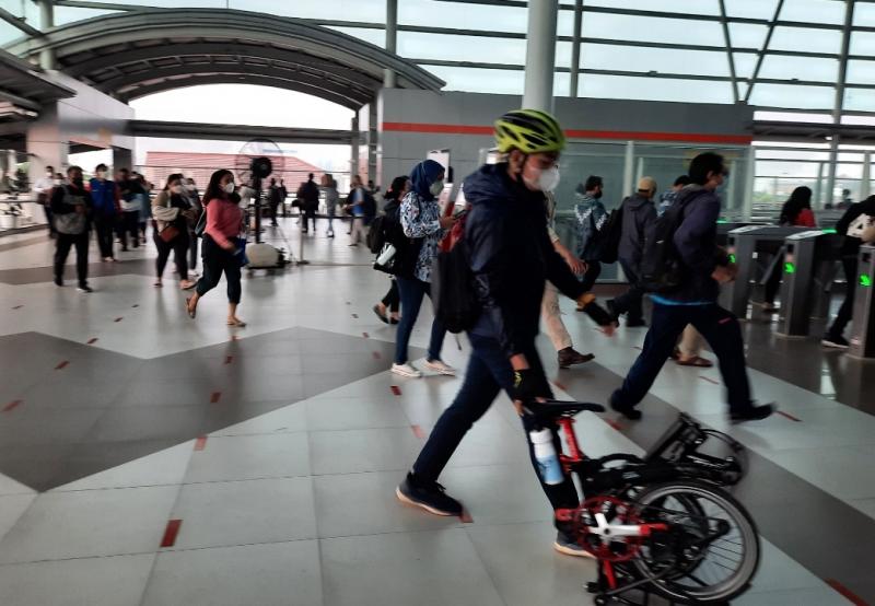 Penumpang dengan sepeda lipat hendak melakukan tap tiket di Stasiun Bakasi, Senin (25/7/2022).