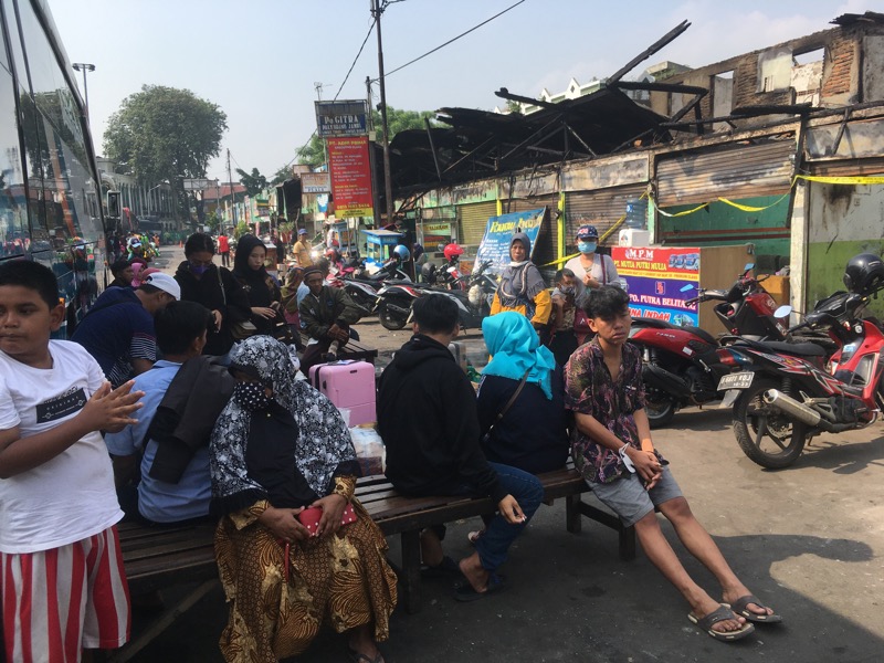 Calon penumpang menunggu dibalik bus Sumatera sebelum ada tenda pascakebakaran loket Sumatera di Terminal Bekasi. Foto: BeritaTrans.com.