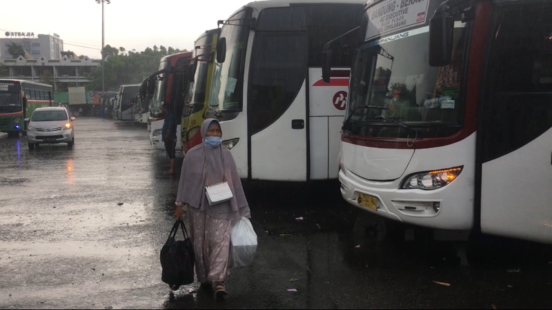 Penumpang bus yang tetap berjalan menuju bus di tengah guyuran hujan di Terminal Bekasi, Kamis (4/8/2022). Foto: BeritaTrans.com.