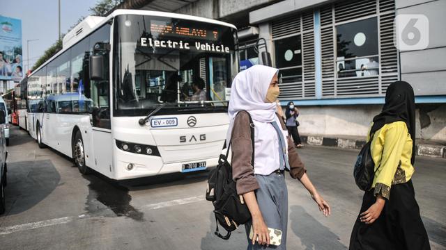Pejalan kaki melintas di depan bus listrik TransJakarta rute Kampung Melayu-Tanah Abang via Cikini (5M) saat uji coba di Terminal Kampung Melayu, Jakarta Timur.