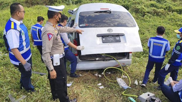Polisi dan petugas Jasamarga mengeluarkan barang di Toyota HiAce. 