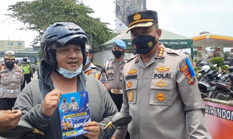 Kapolres Metro Bekasi Kota Kombespol Hengki memakaikan helm kepada pengendara sepeda motor yang terjaring operasi Zebra Jaya di Jalan Ahmad Yani atau di depan gerbang Tol Bekasi Barat, Rabu (12/10/2022).