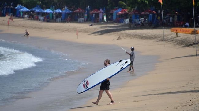 Turis WNA akan berselancara di salah satu pantai di Bali.