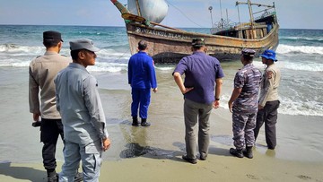 Petugas Bakamla memerhatikan kapal kayu pembawa imigran ilegal Suku Rohingya asal Myanmar yang terdampar di Aceh Besar. (Dok. humas Bakamla)