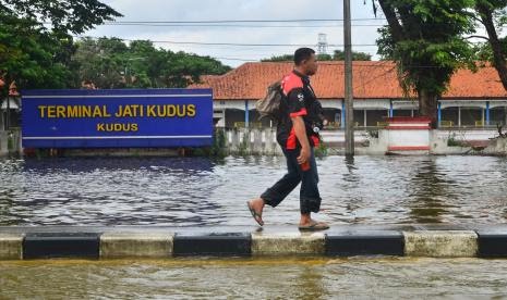 Warga melintasi Terminal Tipe A Jati yang tergenang banjir di Kudus, Jawa Tengah, Ahad (7/2/2021). Terminal Induk Jati di Kudus Lumpuh Akibat Banjir.