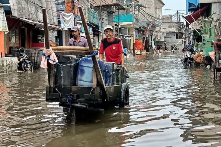 Warga mendorong gerobak di tengah banjir rob yang menerjang wilayah pesisir utara Jakarta.