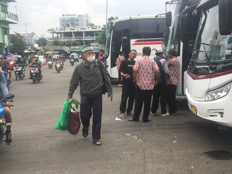 Calon penumpang tengah berjalan di antara bus antarkota di area keberangkatan Terminal Induk Kota Bekasi, Jumat (27/1/2023). Foto: BeritaTrans.com.