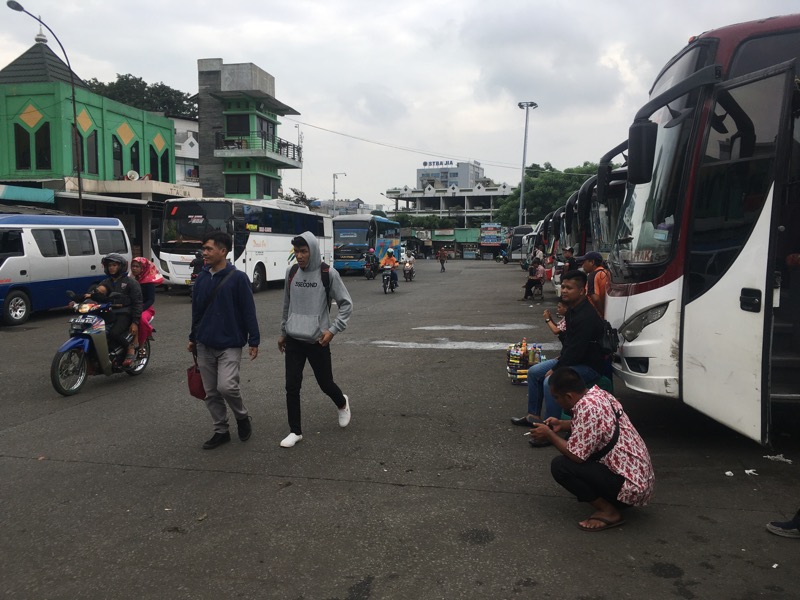 Dua orang berjalan di antar kru dan bus antarkota di area keberangkatan Terminal Induk Kota Bekasi, Selasa (31/1/2023).