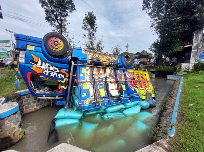 Truk muatan sembilan ton gabah terbalik hingga masuk ke sungai di pinggir Jalan Raya Maospati-Ngawi pada Senin (6/2/2023) pukul 07.00 WIB. Foto: istimewa.