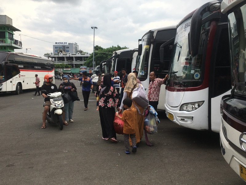 Penumpang berjalan di antara bus antarkota di area keberangkatan Terminal Induk Kota Bekasi, Jumat (10/2/2023) sore.