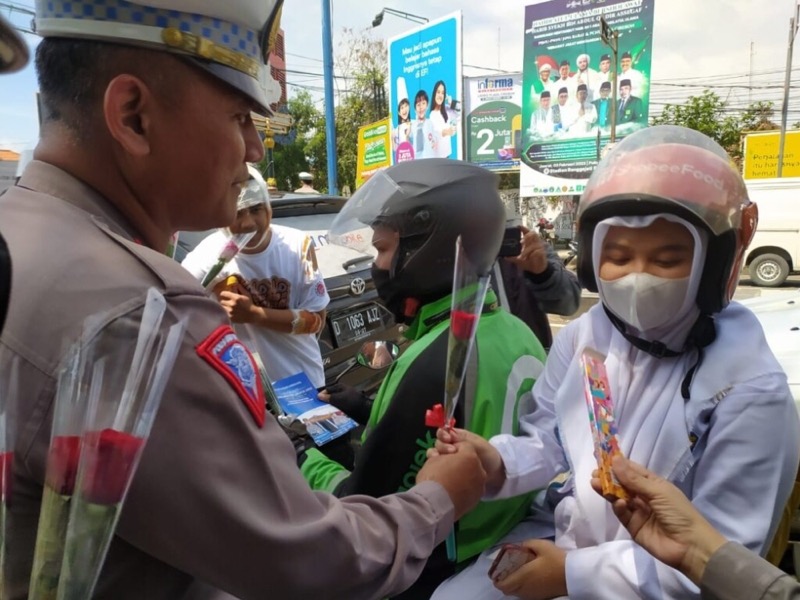 Satlantas Polres Cirebon Kota membagikan helm, bunga, dan coklat bagi pengguna jalan di lampu merah Gunung Sari, Kota Cirebon, Jumat (10/2/2023).