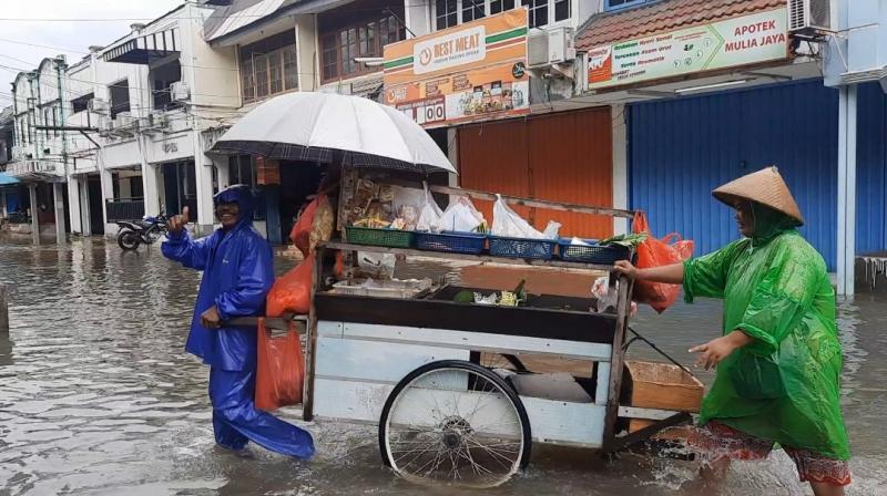 Gerobak sayur beraktivitas di tengah genangan air yang merendam Jalan Taman Narogong Indah, Pengasinan, Kecamatan Rawalumbu, Kota Bekasi, Senin (27/2/2023).
