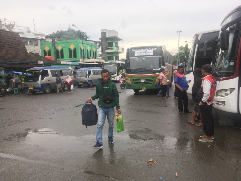 Penumpang bus tengah berjalan di beceknya jalanan Terminal Induk Kota Bekasi, Kamis (2/3/2023) sore.