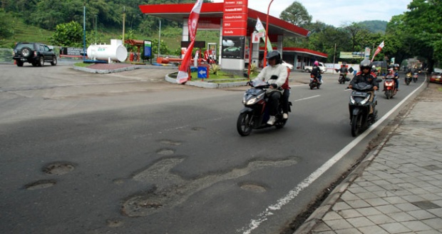 Pengendara sepeda motor menghindari jalan berlubang di Ciherang di jalur tengah Sumedang menuju Cirebon dan Pantura, Jawa Barat, 28 Juni 2016. Kondisi jalan berlubang dan berpasir sampai saat ini belum ada upaya perbaikan. 