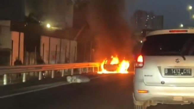 Sebuah mobil Toyota Starlet terbakar di Jalan Tol Kebon Jeruk, tepatnya di depan Kantor Pajak Kebon Jeruk, Jakarta Barat, pada Jumat (24/3/2023). [Dok. Ist]