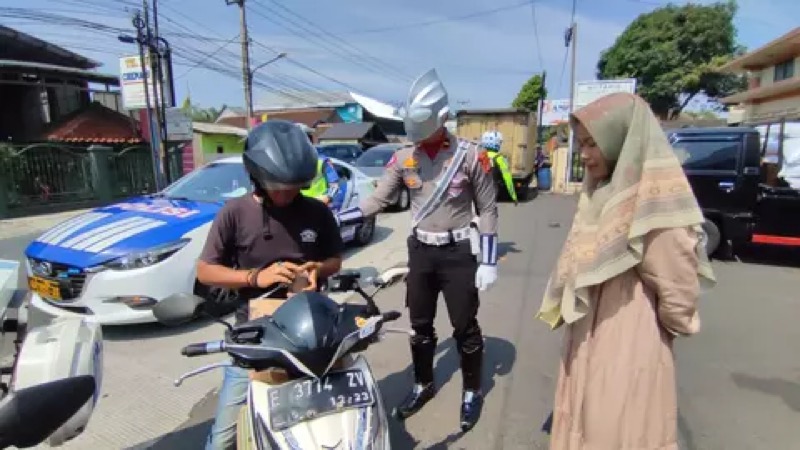 Salah satu anggota dari Satlantas Polres Kuningan menggunakan kostum Ultraman ketika berpatroli.