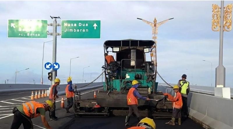 Para pekerja sedang memperbaiki salah satu ruas jalan di Tol Bali Mandara untuk meningkatkan kenyamanan dan keamanan pengguna jalan.