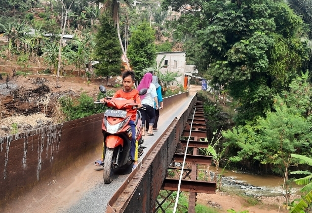Kendaraan sepeda motor dan beberapa warga melintasi jembatan bekas talang air peninggalan Belanda di Kampung Ciherang, Desa Gunungmalang, Kecamatan Cikidang, Kabupaten Sukabumi, Jawa Barat, Ahad (8/10/2023). 