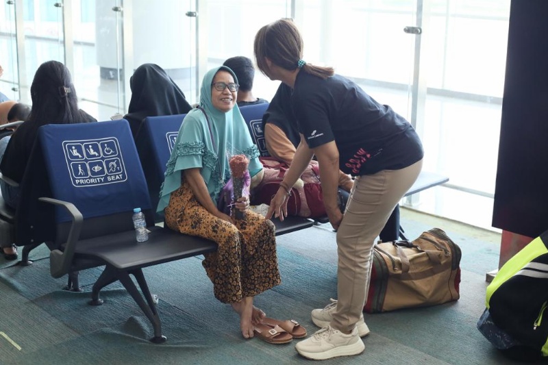 Petugaa Bandara beri sekuntum bunga untuk penumpang Ibu