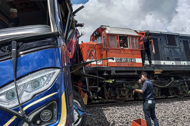 Petugas berusaha mengevakuasi bus penumpang Putra Sulung yang tertabrak kereta api Rajabasa di perlintasan tanpa palang pintu di Jalan Pertanian, Kecamatan Martapura, Kabupaten OKU Timur, Sumatera Selatan, Minggu (21/4/2024). Data sementara dari petugas di lapangan, sebanyak tiga penumpang bus meninggal dunia dan penumpang lainnya mengalami luka-luka. (ANTARA FOTO/T Fikri W)