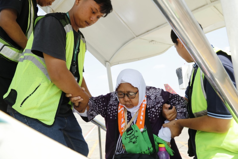 Petugas bantu jemaah haii saat hendak naik pesawat