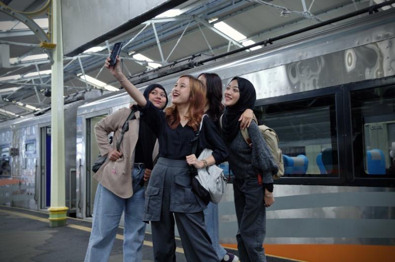 Penumpang di stasiun menikmati perjalanan kereta api. Aplikasi Access by KAI yang memudahkan pelanggan dalam memesan tiket kereta api, LRT, KA Bandara, Whoosh, serta layanan lainnya, menjadikan perjalanan lebih efisien dan nyaman. 