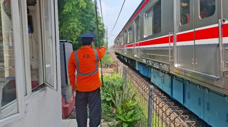 Seorang Petugas Jaga Lintasan (PJL) PT KAI Daop 1 Jakarta menjalankan tugas membuka dan menutup palang pintu perlintasan sebidang di wilayah operasionalnya. Dengan penuh dedikasi, PJL menjadi garda terdepan dalam menjaga keselamatan perjalanan kereta api dan pengguna jalan.