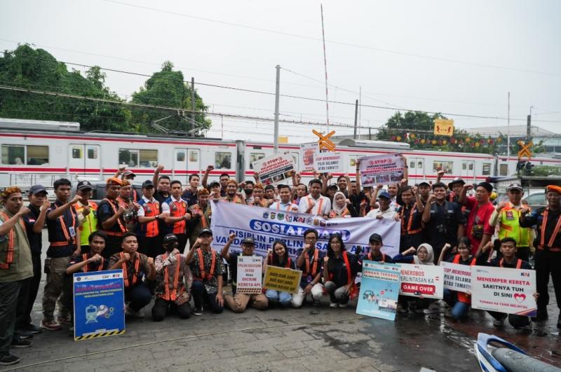 Petugas KAI Daop 1 Jakarta bersama komunitas dan warga membentangkan spanduk imbauan keselamatan di perlintasan sebidang JPL 18 Pejaten Timur, Sabtu (10/5/2025), sebagai bagian dari kampanye keselamatan untuk mencegah kecelakaan.
