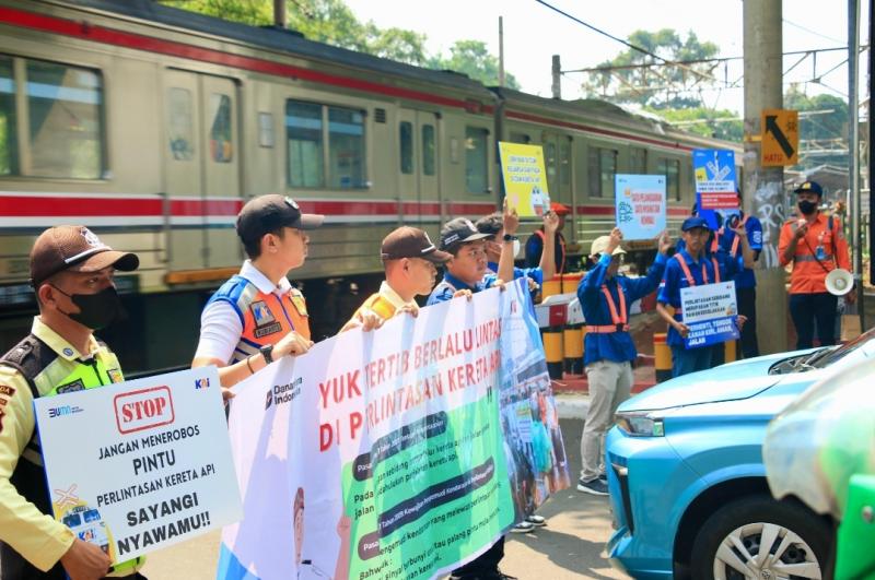 Petugas KAI Daop 1 Jakarta bersama komunitas railfans Train Photograph memberikan edukasi keselamatan kepada pengendara yang melintas di perlintasan sebidang JPL 17 Stasiun Duren Kalibata, Sabtu (19/7/2025). 